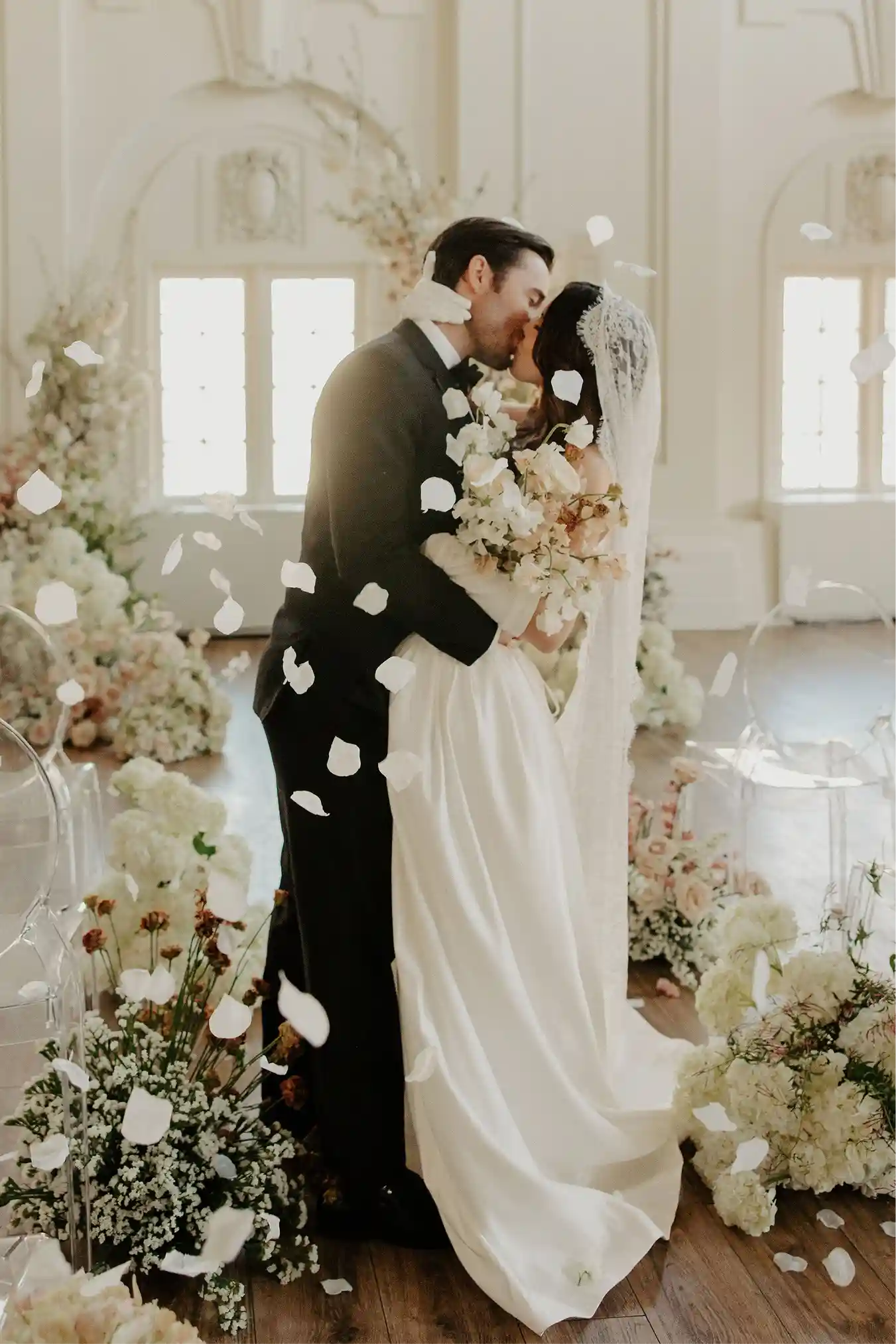 Ceremony couple framed by towering floral arrangements in the ballroom