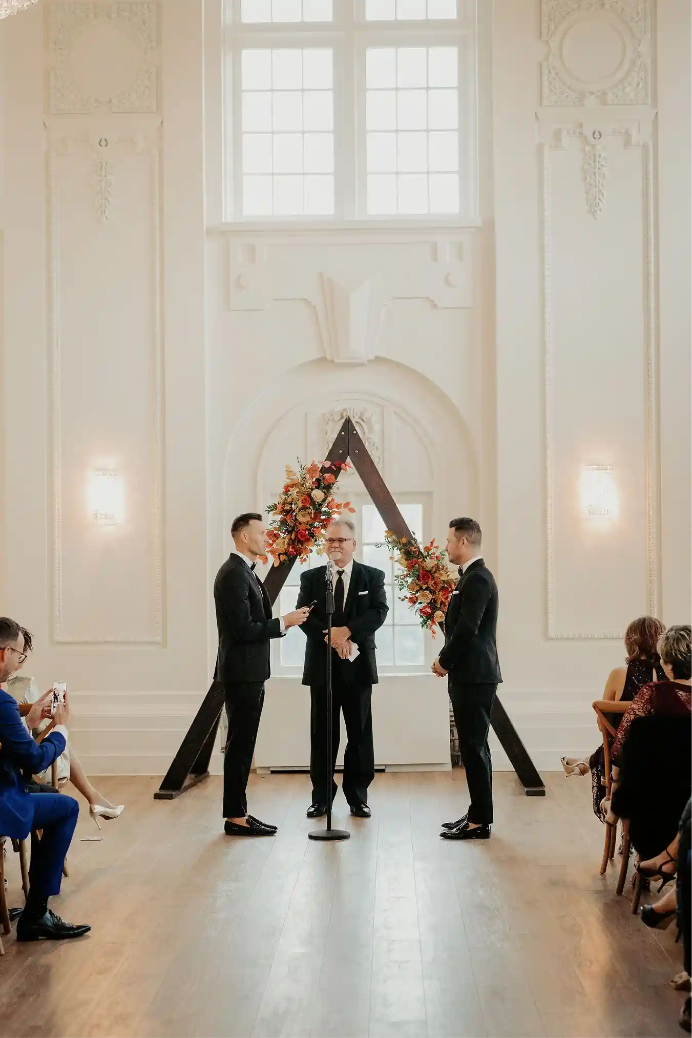 Bride and groom kissing beneath a floral arch inside the venue