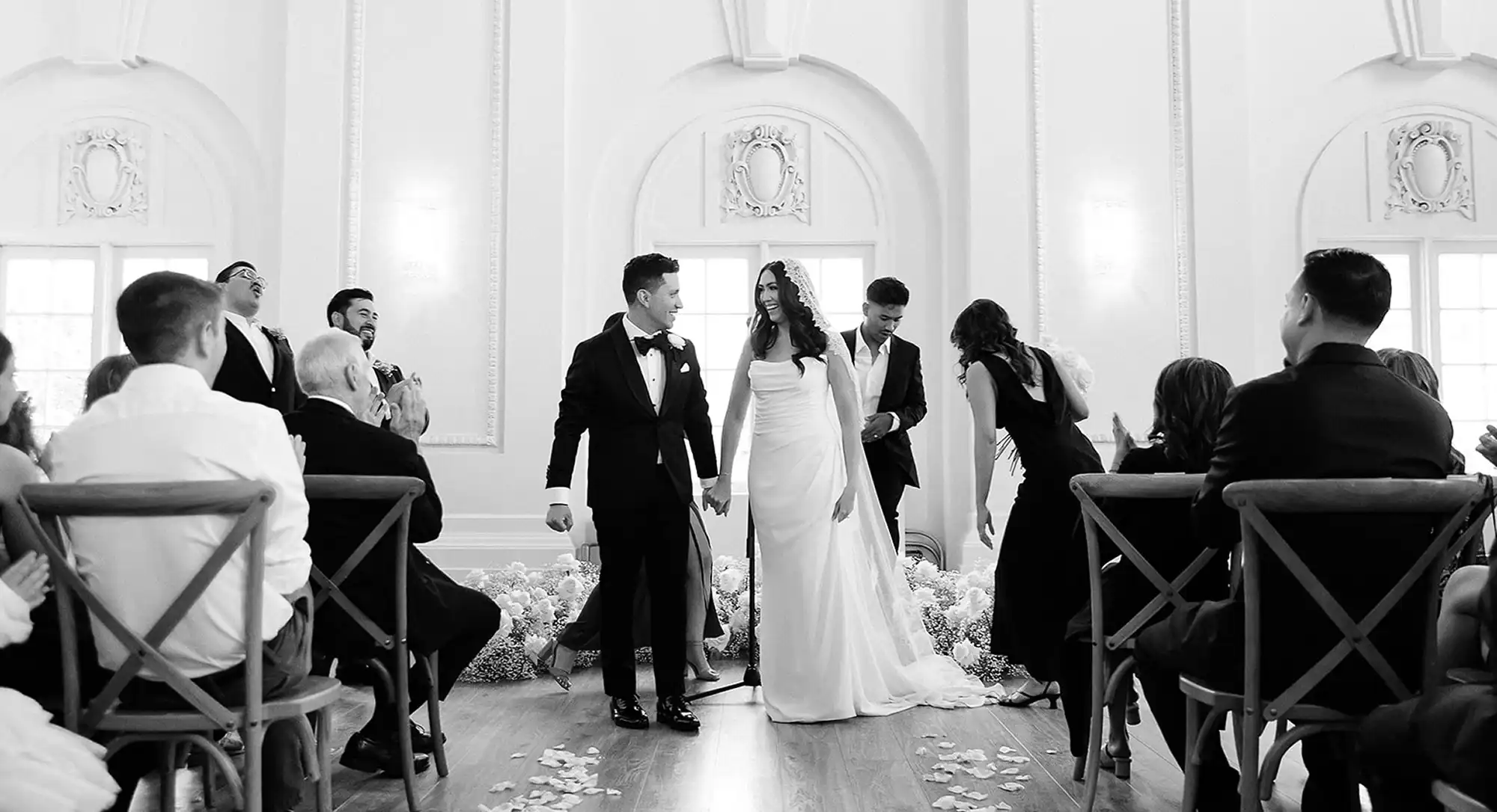 Newlywed couple exiting the venue with guests applauding